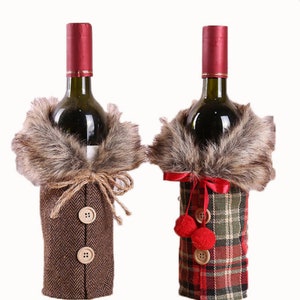 May include: Two wine bottle covers, one brown with a faux fur collar and buttons, the other red and green plaid with a faux fur collar and red pom-poms.