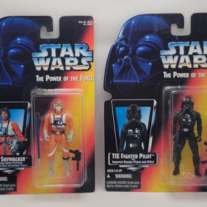 May include: Two Star Wars action figures, "Luke Skywalker" and "Tie Fighter Pilot", in their original packaging. The packaging features Darth Vader's helmet and the text "The Power of the Force". The Luke Skywalker figure is in an orange flight suit.