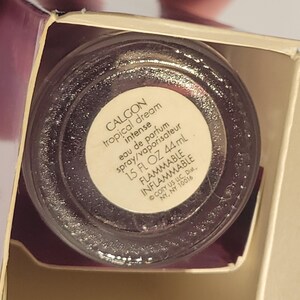Puede incluir: Primer plano de un frasco de perfume Calgon Tropical Dream Intense. La etiqueta dice "eau de parfum spray/vaporisateur 44 ml". El frasco es transparente con un l&iacute;quido oscuro y brillante en su interior. El embalaje es visible.