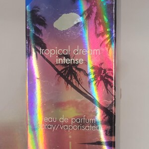 Puede incluir: Caja de perfume Calgon Tropical Dream Intense. La caja tiene un dise&ntilde;o hologr&aacute;fico con palmeras y una puesta de sol. El texto en la caja incluye "Tropical Dream Intense", "eau de parfum" y "take me away!". Contiene 44 ml o 1,5 fl oz.