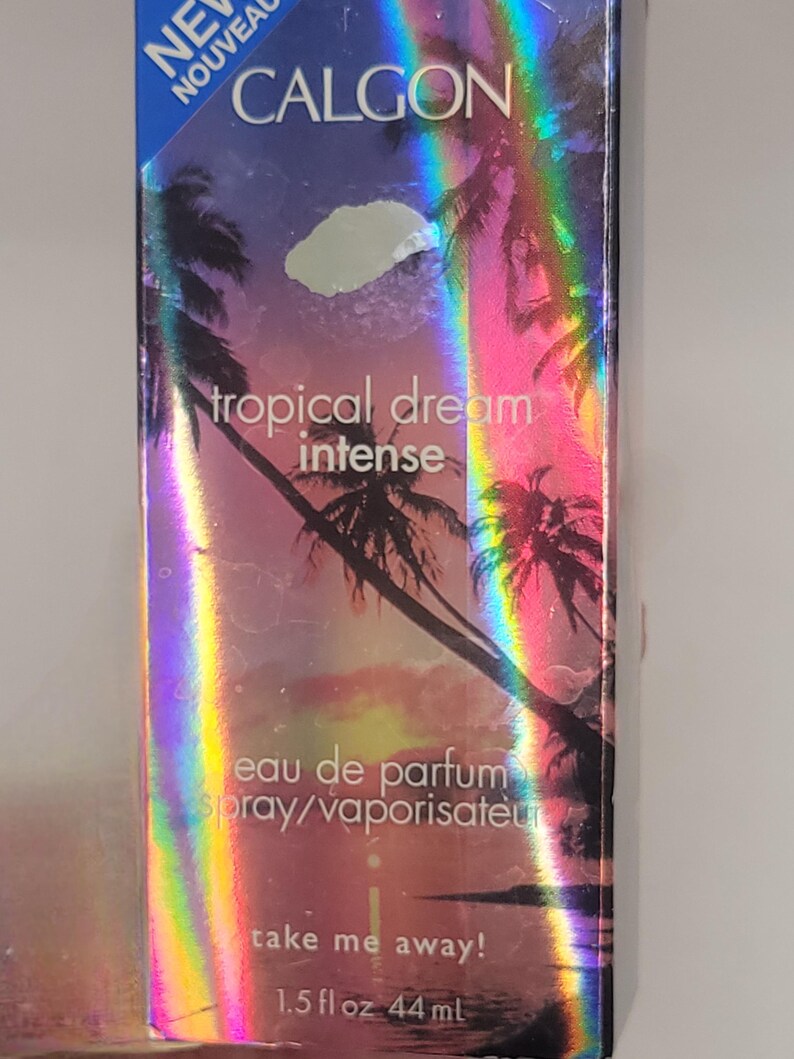 Puede incluir: Caja de perfume Calgon Tropical Dream Intense. La caja tiene un dise&ntilde;o hologr&aacute;fico con palmeras y una puesta de sol. El texto en la caja incluye "Tropical Dream Intense", "eau de parfum" y "take me away!". Contiene 44 ml o 1,5 fl oz.