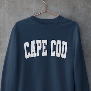 May include: A navy blue sweatshirt with the text "CAPE COD" printed in white on the front.