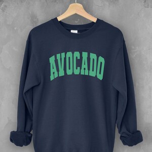 May include: A navy blue sweatshirt with the word "AVOCADO" printed in green in an arched font.