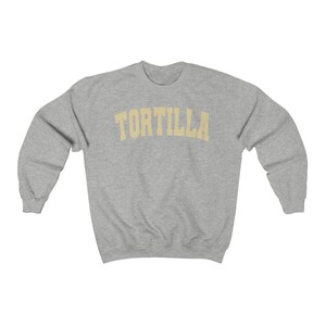 Puede incluir: Una sudadera gris con la palabra "TORTILLA" impresa en un arco amarillo sobre el pecho.