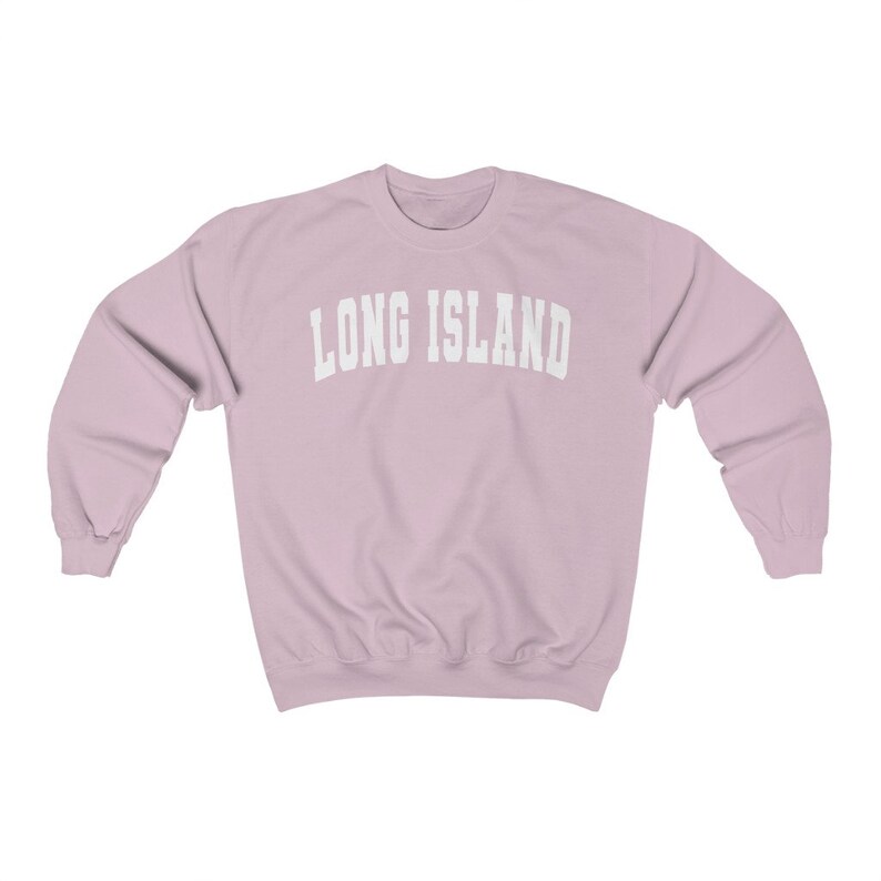 Puede incluir: Una sudadera de color rosa claro con el texto "LONG ISLAND" en blanco, en letras arqueadas.