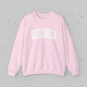May include: A pink sweatshirt with the word "WISCONSIN" printed in white on the front.