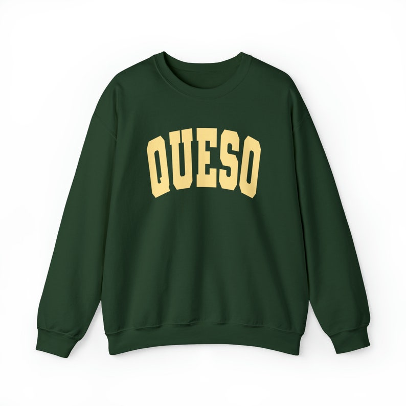 May include: A dark green sweatshirt with the word "QUESO" printed in a yellow-gold color across the chest.