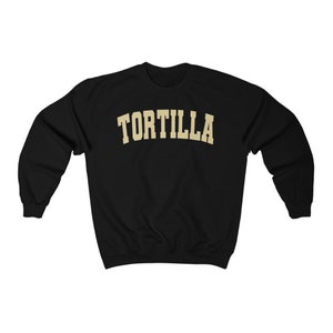 Puede incluir: Sudadera negra con un estampado dorado de "TORTILLA" en la parte delantera.