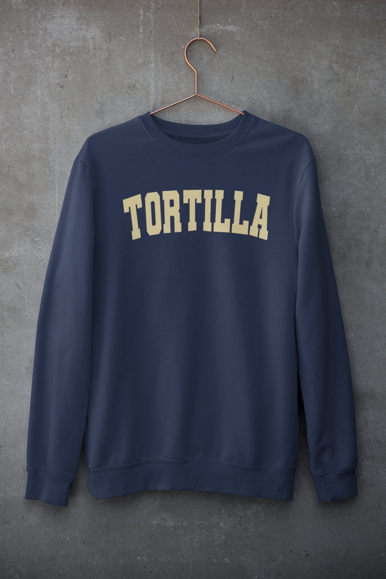 Puede incluir: Una sudadera azul marino con la palabra "TORTILLA" impresa en color crema en el pecho.