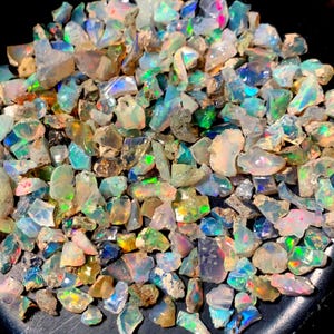 Peut inclure: Une grande collection de pierres précieuses d'opale brute dans différentes nuances de blanc, vert, bleu et brun. Les opales sont irisées et ont une finition naturelle non polie.