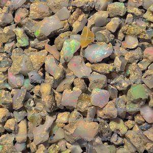 May include: A close-up view of a collection of raw opal stones. The opals display a variety of colors, including white, iridescent, and flashes of green, pink, and blue. The rough stones are mixed with brown and tan matrix.