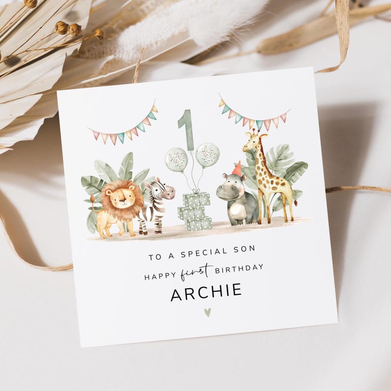 May include: A white birthday card with a watercolor illustration of a lion, zebra, hippo, and giraffe. The card has the text "TO A SPECIAL SON HAPPY FIRST BIRTHDAY ARCHIE". The number "1" and balloons are also featured.