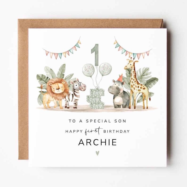 May include: A square birthday card with a brown envelope. The card features watercolor illustrations of a lion, zebra, giraffe, and hippo. Text reads "Happy first birthday Archie" with the number 1 and balloons.