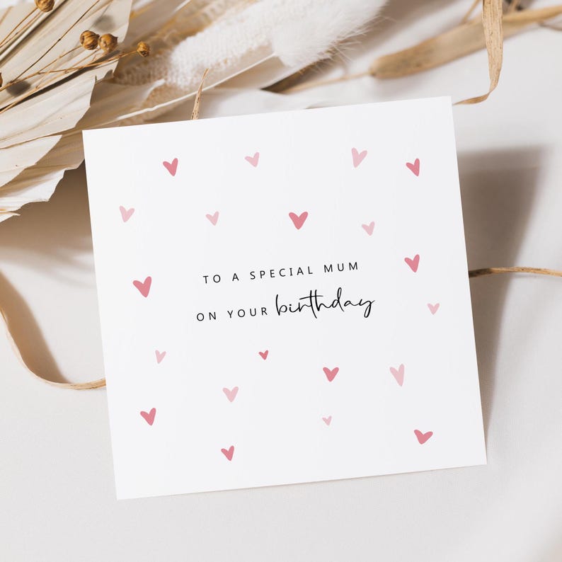 Puede incluir: Una tarjeta blanca con corazones rosas esparcidos por la superficie. La tarjeta dice "To a special Mum on your birthday".