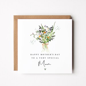 May include: A Mother's Day card featuring a watercolour floral bouquet tied with a ribbon. The card reads "HAPPY MOTHER'S DAY TO A VERY SPECIAL Mum" in black text, with a small green heart below the word "Mum". The card is set in a brown envelope.