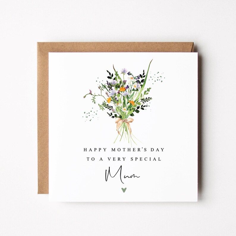 May include: A Mother's Day card featuring a watercolour floral bouquet tied with a ribbon. The card reads "HAPPY MOTHER'S DAY TO A VERY SPECIAL Mum" in black text, with a small green heart below the word "Mum". The card is set in a brown envelope.