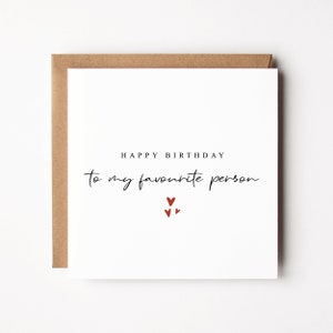 May include: A white card with the text "Happy Birthday to my favourite person" in black script. Three small red hearts are centered below the text.