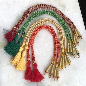 May include: Five sets of braided cords with tassels and metal tips. The cords are red, green, cream, and gold. The tassels are red, green, cream, and gold. The metal tips are gold.