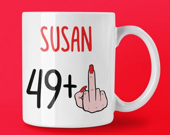 May include: White ceramic mug with the name "SUSAN" in red, the number "49+" in black, and a cartoon illustration of a hand with a red fingernail giving the middle finger.