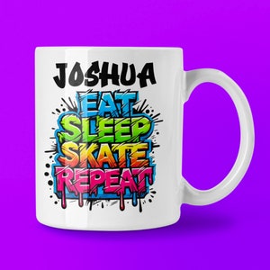 May include: White ceramic mug featuring the name "Joshua" in black, above the words "EAT SLEEP SKATE REPEAT" in a colourful graffiti design. The mug has a curved handle and a purple background.