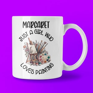 May include: White ceramic mug with the text "Margaret Just a Girl Who Loves Painting." The mug features an illustration of an easel, paintbrushes, a palette, and paint bottles. The mug has a purple background.