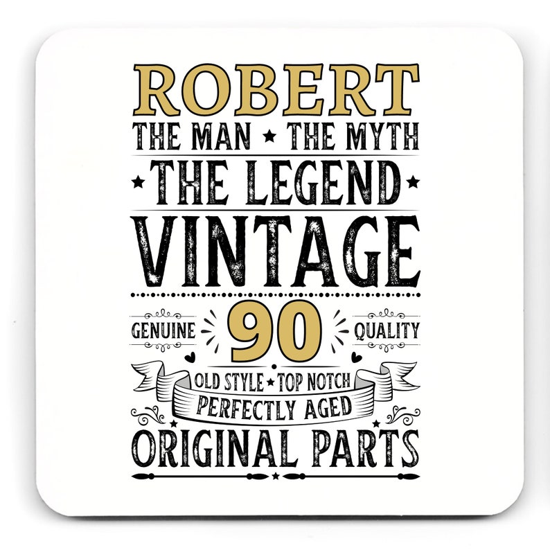 May include: White square coaster with the text "ROBERT THE MAN THE MYTH THE LEGEND VINTAGE 90 GENUINE QUALITY OLD STYLE TOP NOTCH PERFECTLY AGED ORIGINAL PARTS" in black and gold lettering.