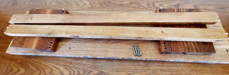 K&ouml;nnte beinhalten: Zwei Holzbretter mit einer braunen Holzbasis und vier silbernen N&auml;geln. Die Bretter sind &uuml;bereinander gestapelt und die Basis befindet sich darunter.