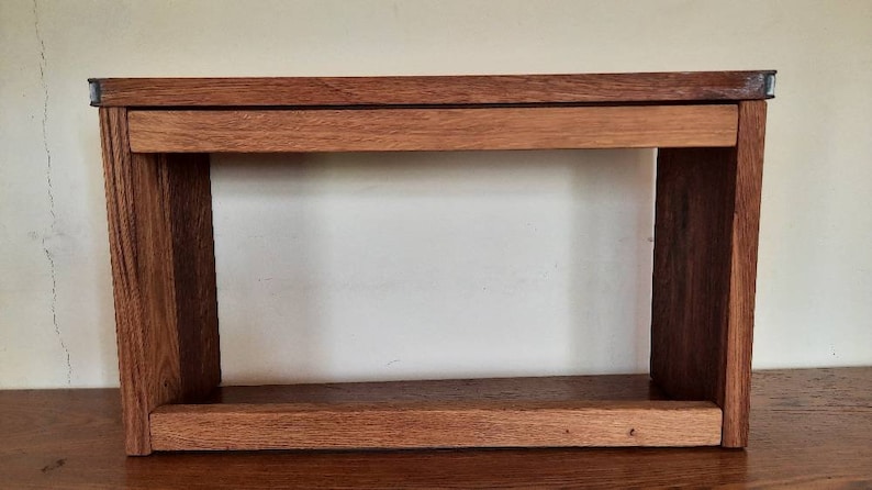 K&ouml;nnte beinhalten: Ein Holzregal mit zwei Regalbrettern und einer Schublade. Das Regal ist aus Naturholz mit einer hellbraunen Oberfl&auml;che. Die Regalbretter sind offen und die Schublade hat einen Metallgriff.