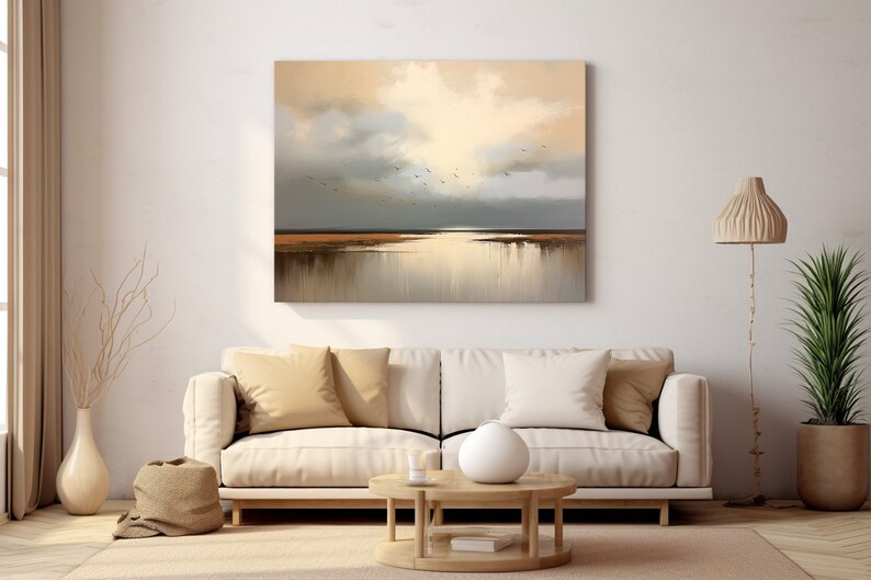 May include: A painting depicting a seascape with a golden sky and a tranquil body of water. The painting is framed and displayed on a white wall in a living room setting.