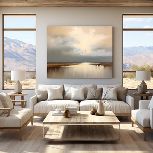 May include: A living room interior featuring a large abstract painting depicting a landscape with a cloudy sky and a body of water. The painting is hung on a wall with a white sofa, two armchairs, a coffee table, and two lamps. The room has large windows offering a view of mountains and a desert landscape.
