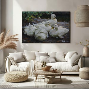 May include: A large rectangular canvas print depicting a group of white ducks with yellow beaks. The ducks are gathered in a natural setting with dark foliage and brown earth tones. The artwork is displayed above a white sofa.