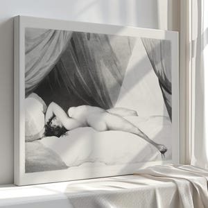 Peut inclure: Impression en noir et blanc encadr&eacute;e d'une figure allong&eacute;e sur un lit, sous un tissu drap&eacute;. L'&oelig;uvre est une repr&eacute;sentation classique d'une personne nue, avec des ombres douces et un travail de ligne d&eacute;taill&eacute;. L'impression est dans un cadre blanc.