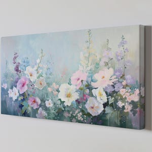 May include: A canvas print of a floral painting in a soft, impressionistic style. The artwork depicts a variety of flowers in shades of pink, white, purple, and blue, creating a gentle and delicate feel. The flowers are painted with visible brushstrokes.