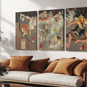 May include: Triptych of Japanese woodblock prints depicting figures in dynamic poses, with vibrant colors and intricate details. The artwork features a dark background with figures in various costumes, creating a dramatic and visually striking composition. The prints are mounted on a wall above a sofa.