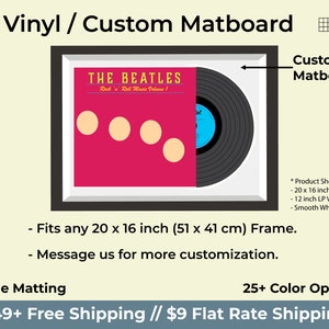 May include: A black and white illustration of a record album with the text "THE BEATLES" and "Rock 'n' Roll Music Volume 1" in a black frame with a white mount. The album is displayed with a custom matboard, which is a type of mounting board used to enhance the presentation of artwork. The matboard is smooth white and fits a 20 x 16 inch frame.