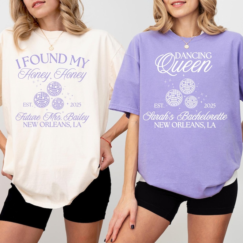 K&ouml;nnte beinhalten: Zwei T-Shirts mit Text und Discokugel-Grafiken. Eines ist cremefarben mit "I FOUND MY Honey, Honey" und "Future Mrs. Bailey, New Orleans, LA". Das andere ist lavendelfarben mit "DANCING Queen" und "Sarah's Bachelorette, New Orleans, LA". Beide Shirts haben "EST. 2025".