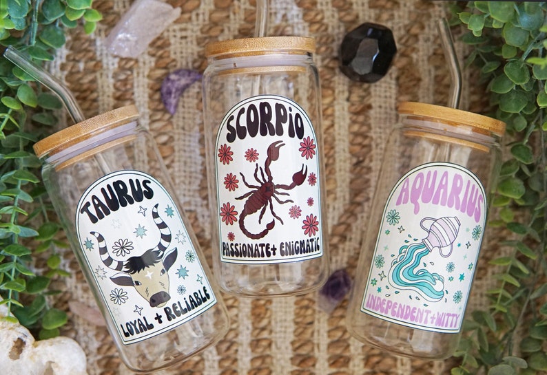 Pode incluir: Tr&ecirc;s copos transparentes para bebidas com tampas de bambu e canudos de vidro. Cada copo apresenta um signo do zod&iacute;aco diferente: Touro, Escorpi&atilde;o e Aqu&aacute;rio. O copo de Touro tem um gr&aacute;fico de touro, o de Escorpi&atilde;o um escorpi&atilde;o.