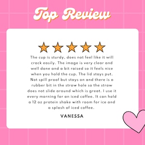 May include: Five gold stars with a pink heart on a pink background. The text "Top Review" is in yellow with a retro font. The text below the stars reads: "The cup is sturdy, does not feel like it will crack easily. The image is very clear and well done and a bit raised so it feels nice when you hold the cup. The lid stays put. Not spill proof but stays on and there is a rubber bit in the straw hole so the straw does not slide around which is great. I use it every morning for an iced coffee. It can hold a 12 oz protein shake with room for ice and a splash of iced coffee. VANESSA"