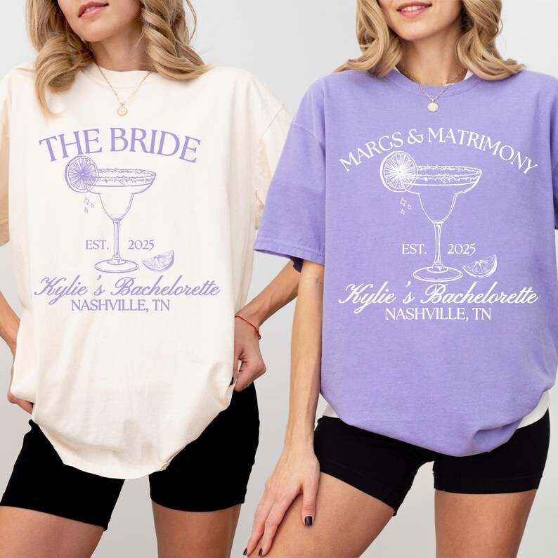 K&ouml;nnte beinhalten: Zwei kurz&auml;rmelige T-Shirts, eines in Creme und eines in Lavendel, jeweils mit einer Grafik eines Margaritaglases mit Limettenspalte sowie dem Text THE BRIDE oder MARGS & MATRIMONY, EST. 2025, Kylie's Bachelorette und NASHVILLE, TN.