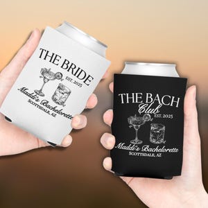 May include: Two black and white can coolers with a bachelorette party theme. One cooler says "The Bride" and the other says "The Bach Club". Both coolers have a cocktail glass and a margarita glass with a lime wedge. The text on both coolers says "Maddi's Bachelorette Scottsdale, AZ" and "EST. 2025".