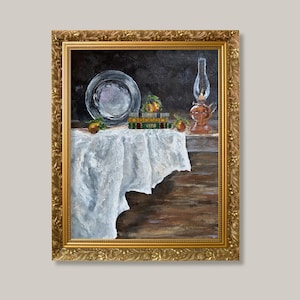 以下が含まれることがあります： 金色の装飾が施された額縁に入った油絵で、白いドレープのかかった布、銀の皿、3冊の本の積み重ね、小さな黄色い果物の房、ガラス製のオイルランプが描かれた静物画。背景は暗く落ち着いた色調で表現されています。