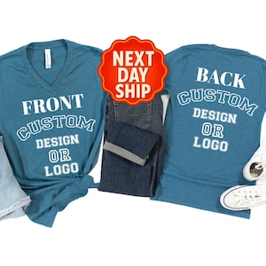 May include: Teal V-neck t-shirts with white text that reads "FRONT CUSTOM DESIGN OR LOGO" and "BACK CUSTOM DESIGN OR LOGO". The shirts are displayed with denim shorts, jeans, and white sneakers. A red and yellow "NEXT DAY SHIP" sticker is also present.