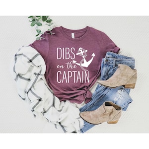 May include: A maroon t-shirt with the text "DIBS on the CAPTAIN" and a white anchor graphic.