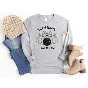 May include: Gray long-sleeve shirt with a black bowling pin graphic and the text "TEAM NAME" and "PLAYER NAME".