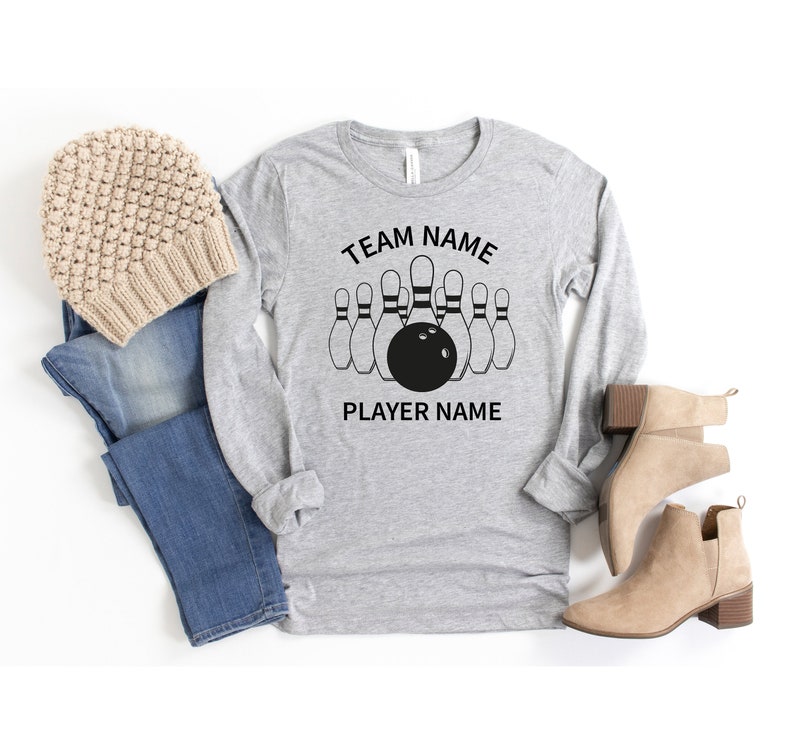 May include: Gray long-sleeve shirt with a black bowling pin graphic and the text "TEAM NAME" and "PLAYER NAME".