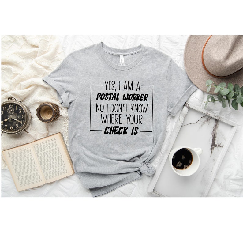 May include: A gray t-shirt with black text that reads "YES, I AM A POSTAL WORKER NO I DON'T KNOW WHERE YOUR CHECK IS".