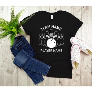 May include: Black t-shirt with a white bowling pin graphic and the text "TEAM NAME PLAYER NAME".