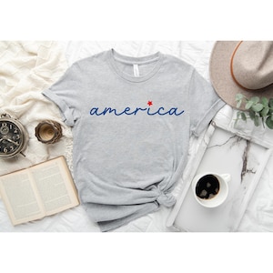 a t - shirt with the word america on it next to a cup of coffee