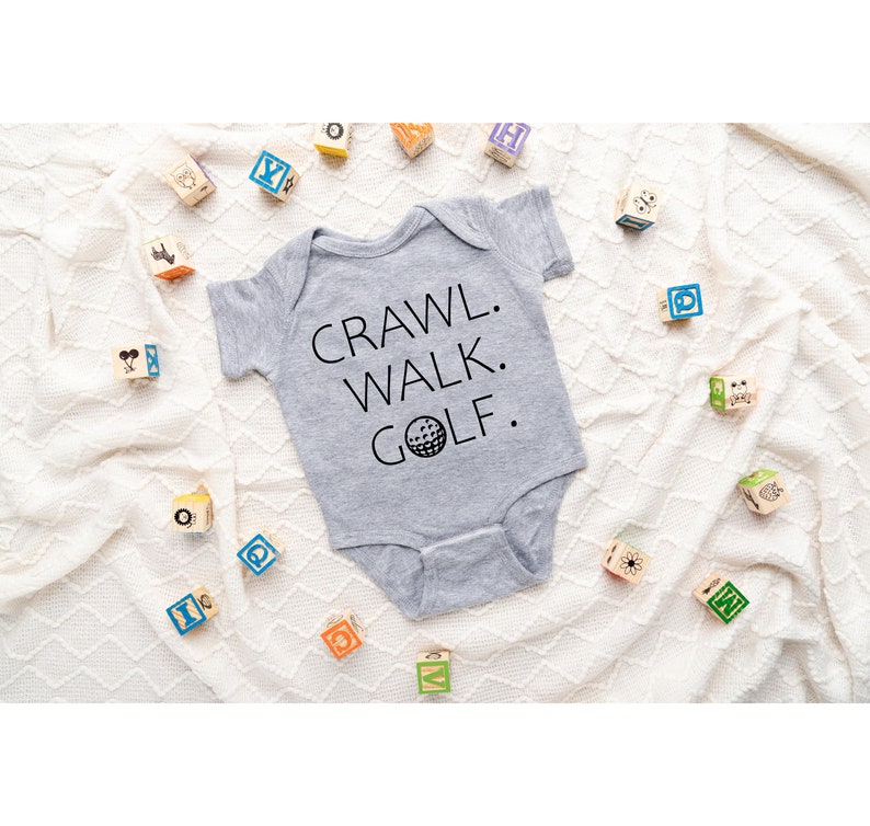 May include: Gray baby onesie with the text "CRAWL. WALK. GOLF." and a golf ball graphic.