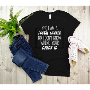May include: Black t-shirt with white text that reads "YES, I AM A POSTAL WORKER NO I DON'T KNOW WHERE YOUR CHECK IS".